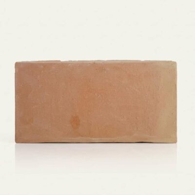 Baldosa rectangular de barro cocido manual en formato 15x30 cm, con tonalidad cálida tierra y superficie rústica ligeramente irregular, acabado mate natural característico del barro.