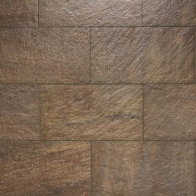 Superficie de gres cerámico con textura rugosa imitación piedra natural en tonos grises y beige, acabado mate antideslizante para suelo.