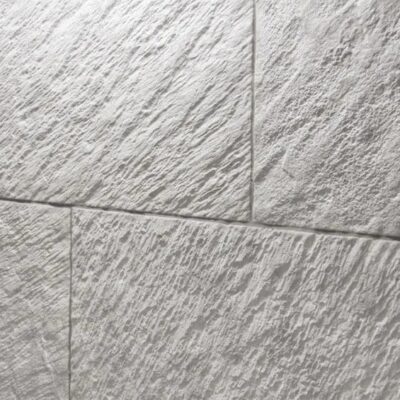 Superficie de gres porcelánico con textura de piedra natural en tonos grises, acabado mate rugoso que simula relieve de cantera.