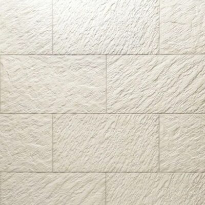 Baldosas rectangulares de gres cerámico en tonos marfil y beige con textura rugosa imitación piedra natural, formato medio en disposición alterna.