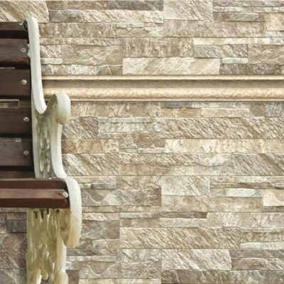 Pared con aplacado de piedra natural en tonos beige y gris, instalado junto a una escalera de madera oscura. El revestimiento muestra un patrón de sillería irregular con texturas naturales y acabado rustico, ideal para suelos ceramico y revestimientos de espacios interiores.
