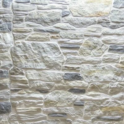 Superficie de gres cerámico con textura de piedra irregular en tonos beige, gris y crema, acabado mate rústico que imita mampostería natural.