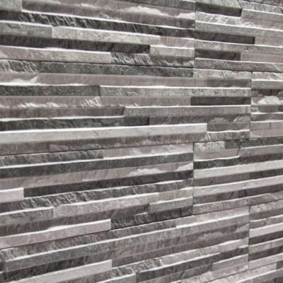 Superficie de gres cerámico con textura de piedra en tonos grises y blancos, exhibiendo un patrón de vetas naturales y acabado mate que imita la rugosidad de la piedra natural.