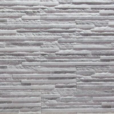 Baldosas rectangulares de gres cerámico en tonos grises con textura de piedra natural y acabado mate. Las piezas muestran un patrón de colocación a tizón con variación cromática entre tonos claros y oscuros.
