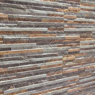 Baldosas rectangulares de gres cerámico con efecto pizarra en tonos grises, marrones y beige, dispuestas en patrón de stacking horizontal. Acabado con textura natural de piedra y variación cromática realista.