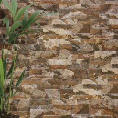 Superficie de gres cerámico con acabado texturizado que imita piedra natural en tonos marrón, beige y gris. Textura rugosa y mate con variaciones de color que crean profundidad visual.