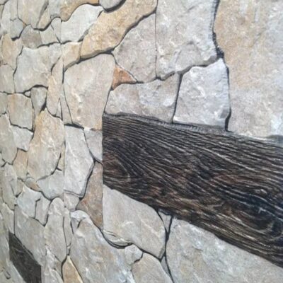 Superficie de gres cerámico con acabado mate que imita piedra natural, mostrando textura irregular con tonos beige, crema y gris claro, vetas oscuras y fracturas características del material.