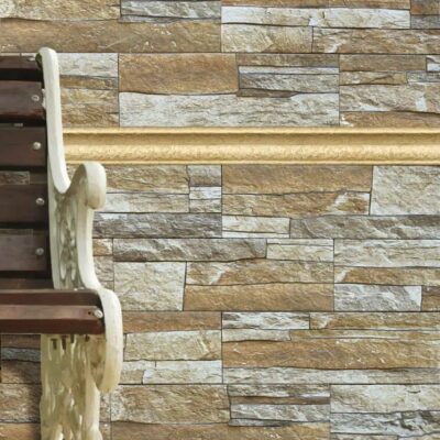 Revestimiento de pared con gres cerámico efecto piedra en tonos beige y crema, instalado en formato rectangular irregular. Escalera de madera con pasamanos blanco adosada a la pared, mostrando la aplicación del suelo cerámico en un contexto residencial.