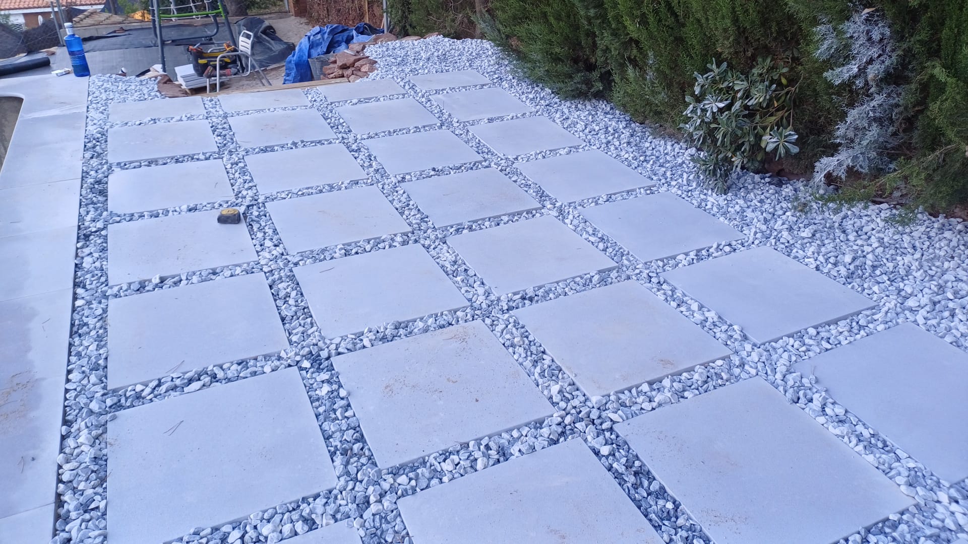 Proceso de instalación de baldosas de hormigón sobre un lecho de arena bien nivelado.
