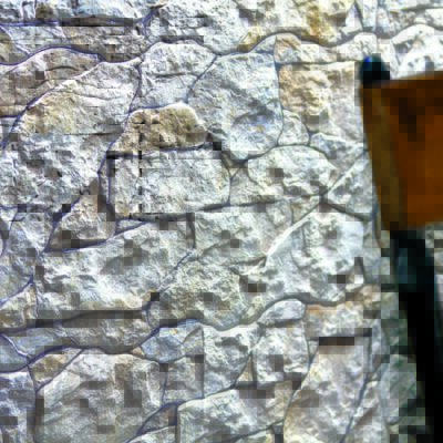 Superficie de aplacado con textura de piedra natural gris claro y tonos beige, mostrando relieve irregular y acabado rústico mate con juntas oscuras entre piezas.