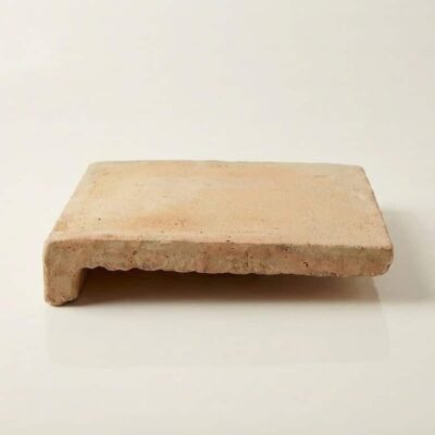 Peldaño de barro natural con forma rectangular y perfil lateral cuadrado. Superficie de color beige claro con textura rústica y acabado mate, mostrando los bordes irregulares características del barro cocido tradicional.