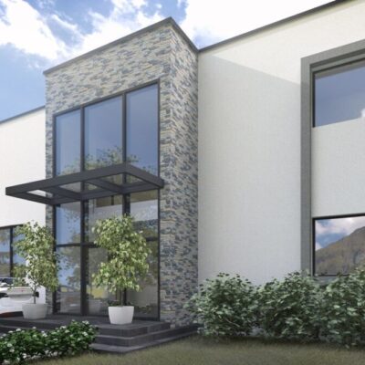 Fachada contemporánea con revestimiento de piedra gris en tonos claros combinado con paramento blanco liso. La composición muestra grandes ventanales con marco oscuro, entrada techada y vegetación circundante en entorno de montaña.