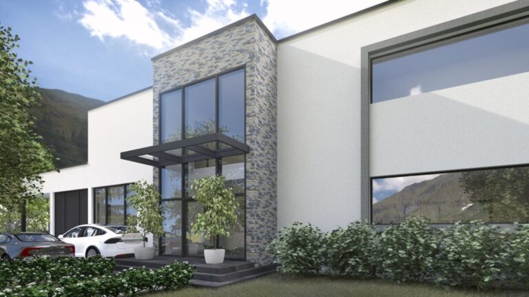 Fachada contemporánea con revestimiento de piedra gris en tonos claros combinado con paramento blanco liso. La composición muestra grandes ventanales con marco oscuro, entrada techada y vegetación circundante en entorno de montaña.