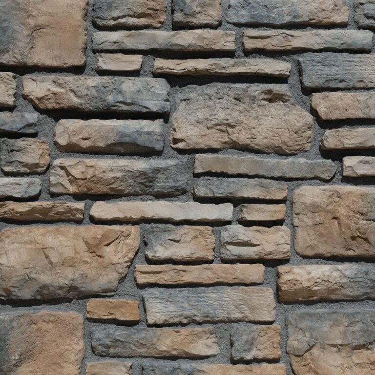Piezas rectangulares de revestimiento con textura rústica imitación piedra natural en tonos beige, gris y marrón, dispuestas en patrón de despiece irregular con acabado mate y relieve pronunciado.