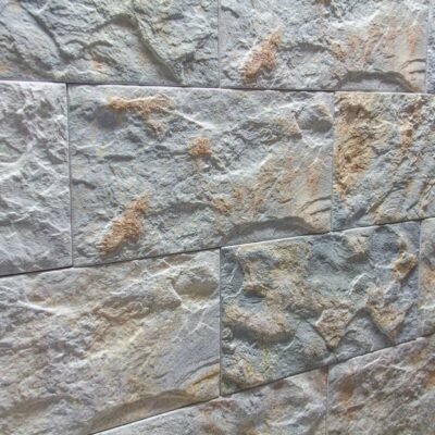 Superficie de revestimiento con textura irregular y relieve pronunciado en tonos grises y beige, acabado rústico mate que imita piedra natural.