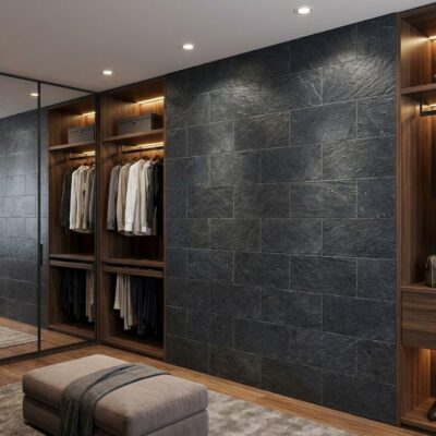 Vestidor de lujo con revestimiento de pared en gres porcelánico grafito Baikal de formato grande, acabado mate con textura de pizarra, combinado con muebles de madera clara iluminados y puertas espejadas.