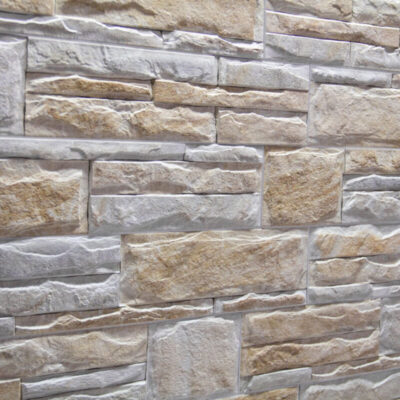 Piezas rectangulares de gres porcelánico con acabado efecto piedra natural en tonos beige y gris. Superficie texturizada con relieve irregular y formato stacked, simulando mampostería de piedra.