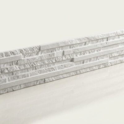 Pieza rectangular de azulejo cerámico con acabado efecto piedra en tonos blancos y grises. Superficie texturizada con relieve que imita piedra natural, combinando bandas lisas y áreas rugosas.
