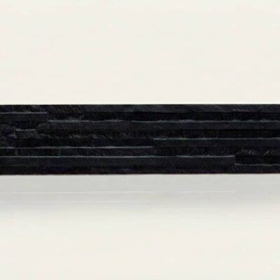 Baldosa cerámica rectangular en tono negro con textura que imita piedra natural, acabado mate. Pieza de formato alargado sobre fondo neutro.