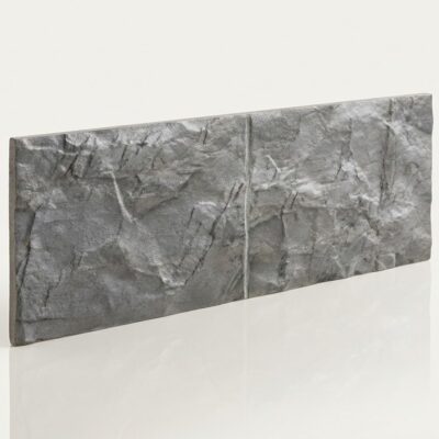 Pieza rectangular de azulejo cerámico con acabado imitación piedra en tonos grises. Superficie texturizada con relieve que simula piedra natural, presentando variaciones de color gris y blanco.