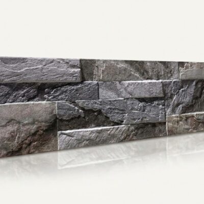 Piezas rectangulares de azulejo con efecto piedra natural en tonos grises, superficie texturizada y acabado mate que imita la piedra cantera, apiladas en composición escalonada.