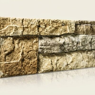 Pieza rectangular de azulejo con acabado efecto piedra en tonos beige y gris. Superficie texturizada con relieve que imita mampostería natural, presentando variaciones de color y un acabado mate rústico.