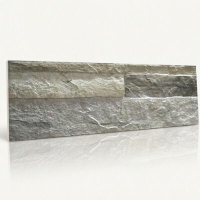 Pieza rectangular de azulejo con textura de piedra natural en tonos grises. Superficie rugosa y mate con variaciones de color que imitan la piedra, acabado rústico.