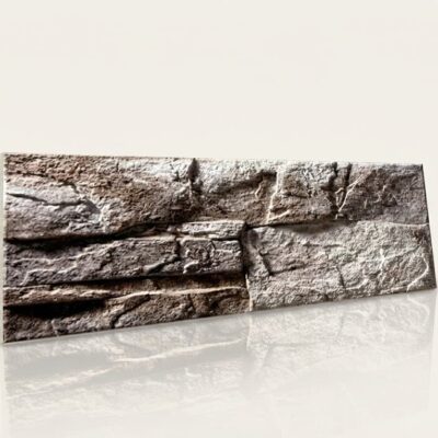 Pieza rectangular de azulejo con textura irregular imitando piedra natural en tonos grises. Superficie rugosa y porosa con variaciones de color que crean profundidad y autenticidad en el acabado mate.
