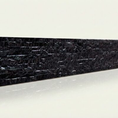 Baldosa cerámica rectangular con acabado mate que imita la textura rugosa de la piedra natural en tonalidad negra con vetas gris claro.