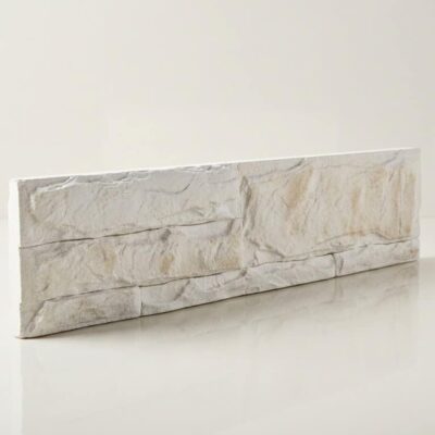 Pieza rectangular de azulejo con acabado imitación piedra natural en tonos blancos y beige, superficie texturizada con efecto de bloques irregulares apilados, acabado mate.