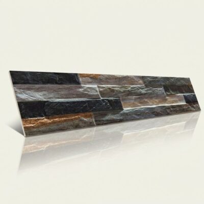Pieza rectangular de azulejo con efecto piedra natural en tonos grafito, negro y gris. Superficie con textura irregular y veteado que imita la piedra natural, acabado mate. Formato alargado horizontal.