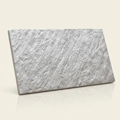 Baldosa cerámica rectangular de color gris con textura rugosa imitación piedra, acabado mate y superficie con relieve irregular.