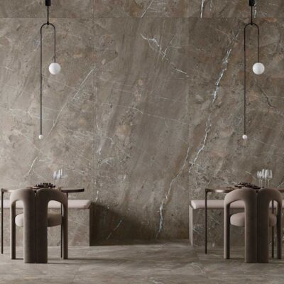Interior minimalista con paredes revestidas en gres porcelánico efecto piedra natural en tonos grises y beige, suelo continuo a juego, muebles cilíndricos de diseño contemporáneo y lámparas colgantes geométricas.