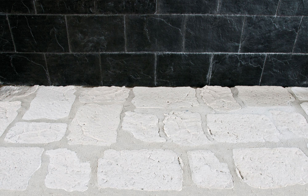 Baldosas rectangulares de gres antideslizante con acabado rústico en tonos beige y gris claro, superficie texturizada que imita piedra natural, formato suelo cerámico.