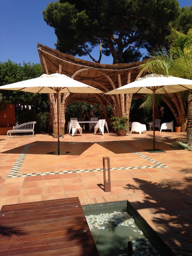 Terraza exterior con un elegante suelo de baldosas de barro cocido y mobiliario moderno de madera.