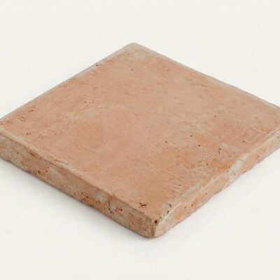 Baldosa cuadrada de barro cocido manual con formato 15x15 cm, superficie mate con textura rústica irregular y tonalidad tierra cálida, visible en los bordes el grosor característico del material artesanal.