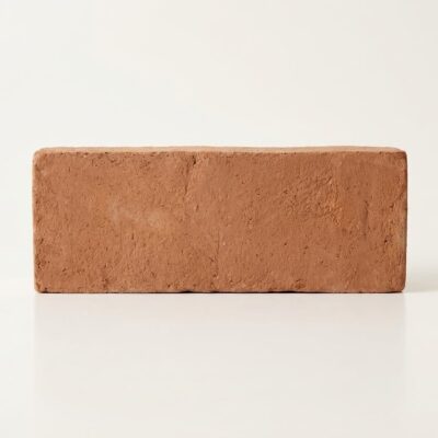 Pieza rectangular de barro cocido artesanal en formato 10x30 cm con superficie rugosa y textura natural. Tonalidad cálida terra con variaciones sutiles inherentes al proceso manual de fabricación.