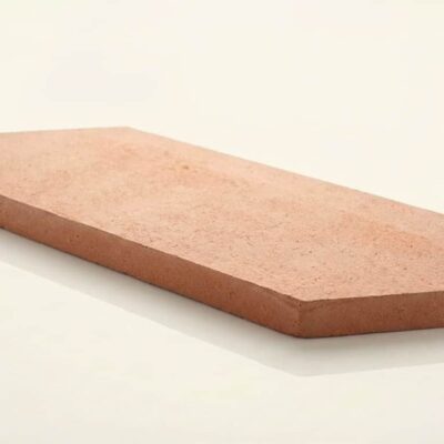 Pieza de barro cocido con forma de rombo alargado, tonos cálidos arena y terracota, superficie mate rústica con textura natural característica del barro cocido.