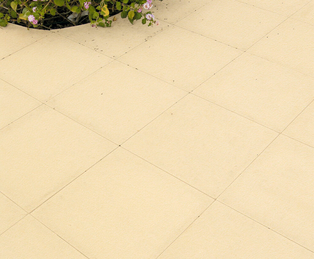 Baldosa de hormigón rectangular en tono crema con acabado mate uniforme y juntas visibles. Superficie lisa y homogénea, ideal para pavimentación de exteriores y terrazas.