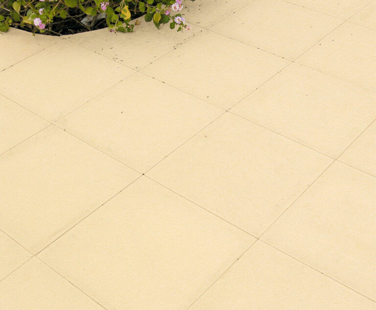 Baldosa de hormigón rectangular en tono crema con acabado mate uniforme y juntas visibles. Superficie lisa y homogénea, ideal para pavimentación de exteriores y terrazas.