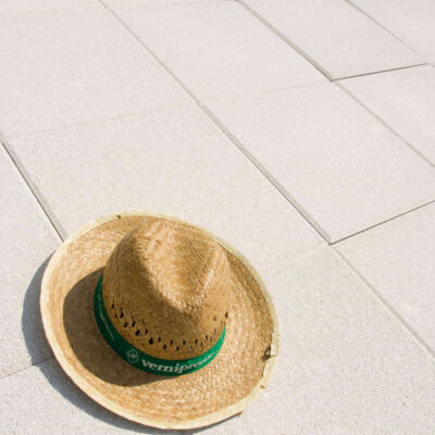 Sombrero de tejido de paja natural con banda verde de la marca Verniprens, colocado sobre baldosa cerámica de color claro.