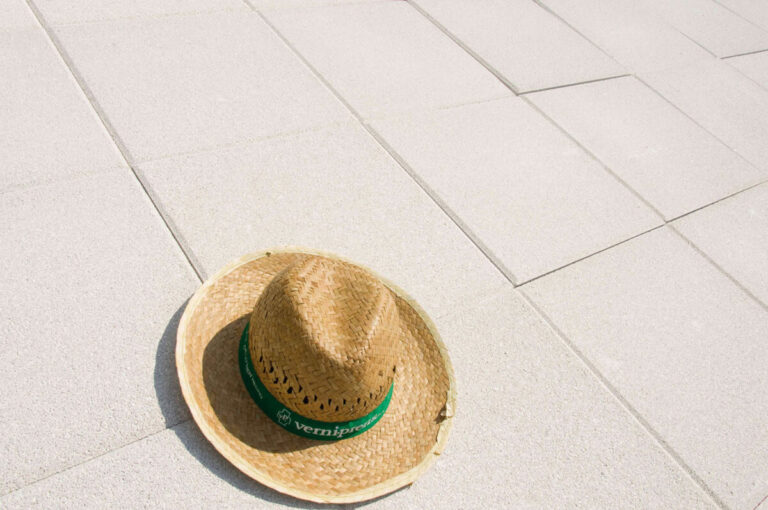 Sombrero de tejido de paja natural con banda verde de la marca Verniprens, colocado sobre baldosa cerámica de color claro.