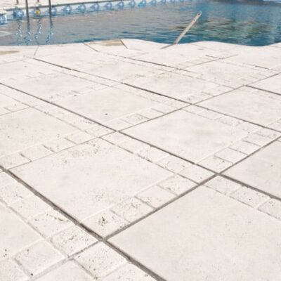 Terraza junto a piscina con baldosas de hormigón gris claro en formato rectangular. Las piezas están dispuestas en patrón continuo, mostrando una superficie lisa y uniforme ideal para suelo porcelánico de exterior.