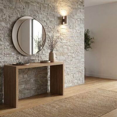 Recibidor contemporáneo con aplacado de pared en efecto piedra color marfil, consola de madera, espejo redondo y puerta corredera de cristal al fondo.