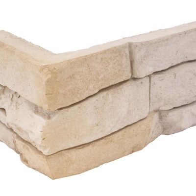 Pieza de revestimiento en forma de esquina con textura rugosa imitación piedra natural en tonos beige y crema. Formato irregular con bordes irregulares característicos de aplacado de hormigón.