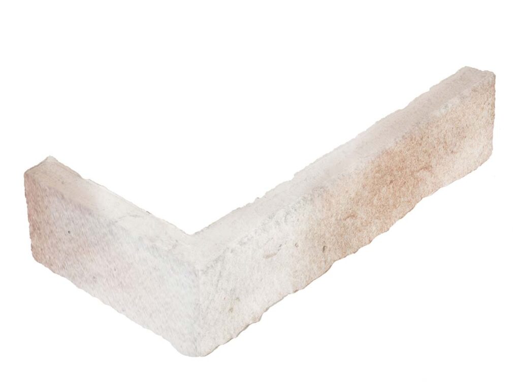 Pieza angular de aplacado en hormigón aligerado con textura rústica imitación ladrillo Oxford en tonalidad blanca y beige. Formato irregular con acabado mate y aspecto envejecido característico de mampostería.