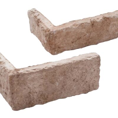 Dos piezas de aplacado de hormigón con acabado rústico imitando piedra natural en tonos beige y marrón claro. Presentan bordes irregulares y textura rugosa característica, formato esquina y pieza recta para revestimiento de pared.