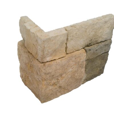Pieza irregular de aplacado en hormigón con efecto piedra natural, tonos beige y grises con textura rústica y acabado mate. Esquina formada por dos bloques superpuestos para revestimiento de pared.