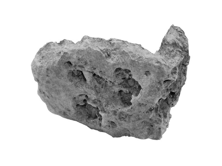 Pieza irregular de aplacado hormigón con textura rugosa imitación piedra natural, tonos grises y blanquecinos, acabado mate con relieve y porosidad característica.