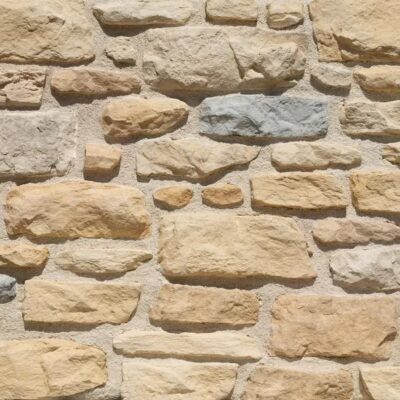 Aplacado de hormigón imitación piedra en tonos beige y marrón con textura irregular y superficie rugosa, piezas de formato variable y grosor pronunciado para revestimiento de pared.